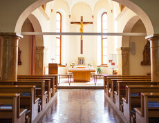 Die Kappele mit Kirchenbänken rechts und links, sowie den Altar in der Mitte. Über diesem hängt ein großes Kreuz.