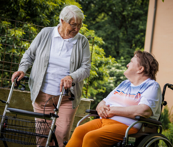 Im großzügigen Garten sprechen zwei Bewohner*innen miteinander. 