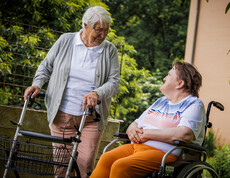 Im großzügigen Garten sprechen zwei Bewohner*innen miteinander. 