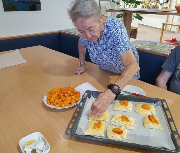 Ältere Dame steht beim Tisch und befüllt Teigtaschen.