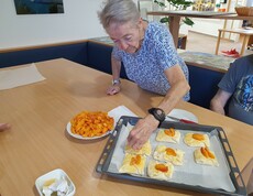 Ältere Dame steht beim Tisch und befüllt Teigtaschen.