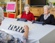 Drei Bewohnerinnen sitzen am Tisch und spielen Rummikub.