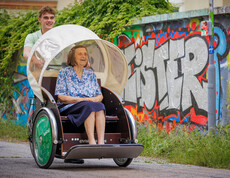 Ein Zivildiener fährt mit der Rikscha des Hauses, in der eine Bewohnerin sitzt in die Stadt. 