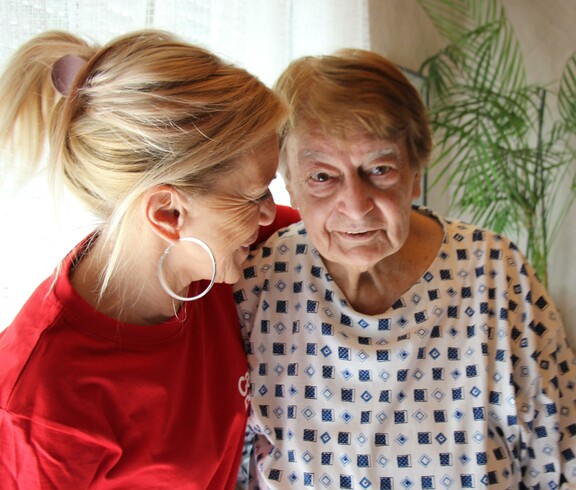 Caritas Mitarbeiterin der Hauskrankenpflege mit einer Klientin im Arm