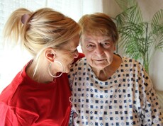 Caritas Mitarbeiterin der Hauskrankenpflege mit einer Klientin im Arm