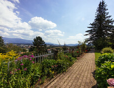 Bäume und bunte Sträucher befinden sich in unserer schönen Gartenanlage, welche auch einen tollen Ausblick auf die Landschaft wirft.