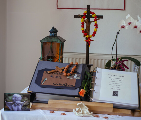 Traueraltar mit Verabschiedungsbuch, Christuskreuz, 2 Engel, Engel-Postkarte, Grablaterne und einer Blume.