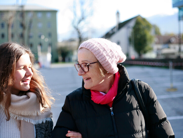 Eine junge Frau und eine Pensionistin Arm in Arm