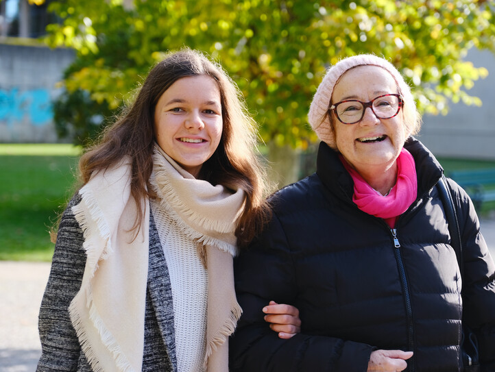 Eine junge Frau und eine Pensionistin Arm in Arm