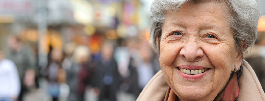 Portrait einer Seniorin in einer Fußgängerzone.
