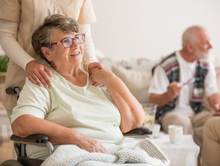 Happy senior lady sitting at wheelchair in nursing home for elderly